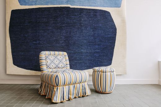 And Objects upholstered chair in Boundary striped check fabric, featuring navy blue and ochre yellow stripes, with a frilled skirt, paired with a Boundary striped footstool. Classic modern design, displayed in the Christopher Farr Cloth London Chelsea King's Road showroom.  Photography by Christopher Horwood 