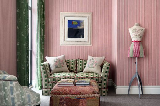 Sofa upholstered in Lost and Found Green by Kit Kemp in a pink and green interior at Firmdale’s Ham Yard Hotel. Features striped wallpaper, geometric shapes, and artisan modern style, photo by Christopher Horwood.
