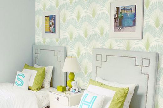 Twin bedroom featuring Brisa Printed Wallpaper in the Aruba colourway on the walls, styled with lime green and aqua accessories for a fresh, vibrant look. A playful yet elegant design using Michael Szell’s feather fan pattern for Christopher Farr Cloth.